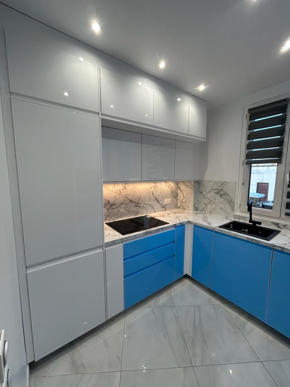 Cuisine rénovée avec façades bleues, meubles hauts blancs et plan effet marbre